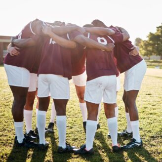 A group of men huddle on a sports field.