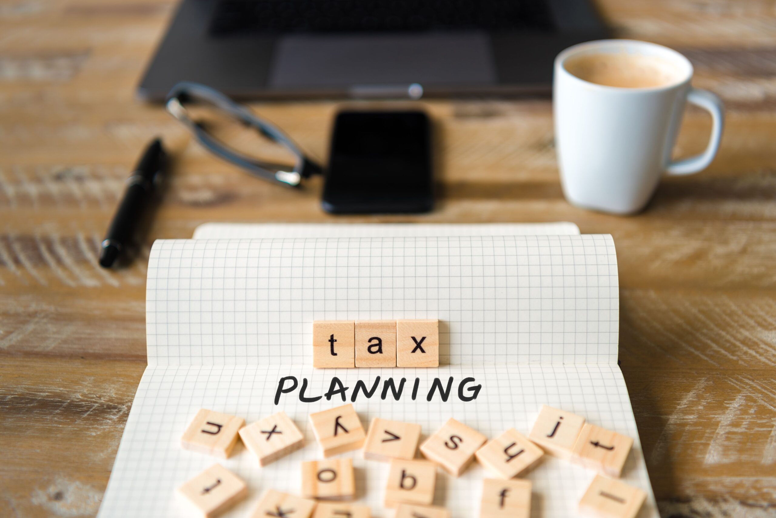 Lettered tiles scattered on a notepad that spell out Tax Planning.