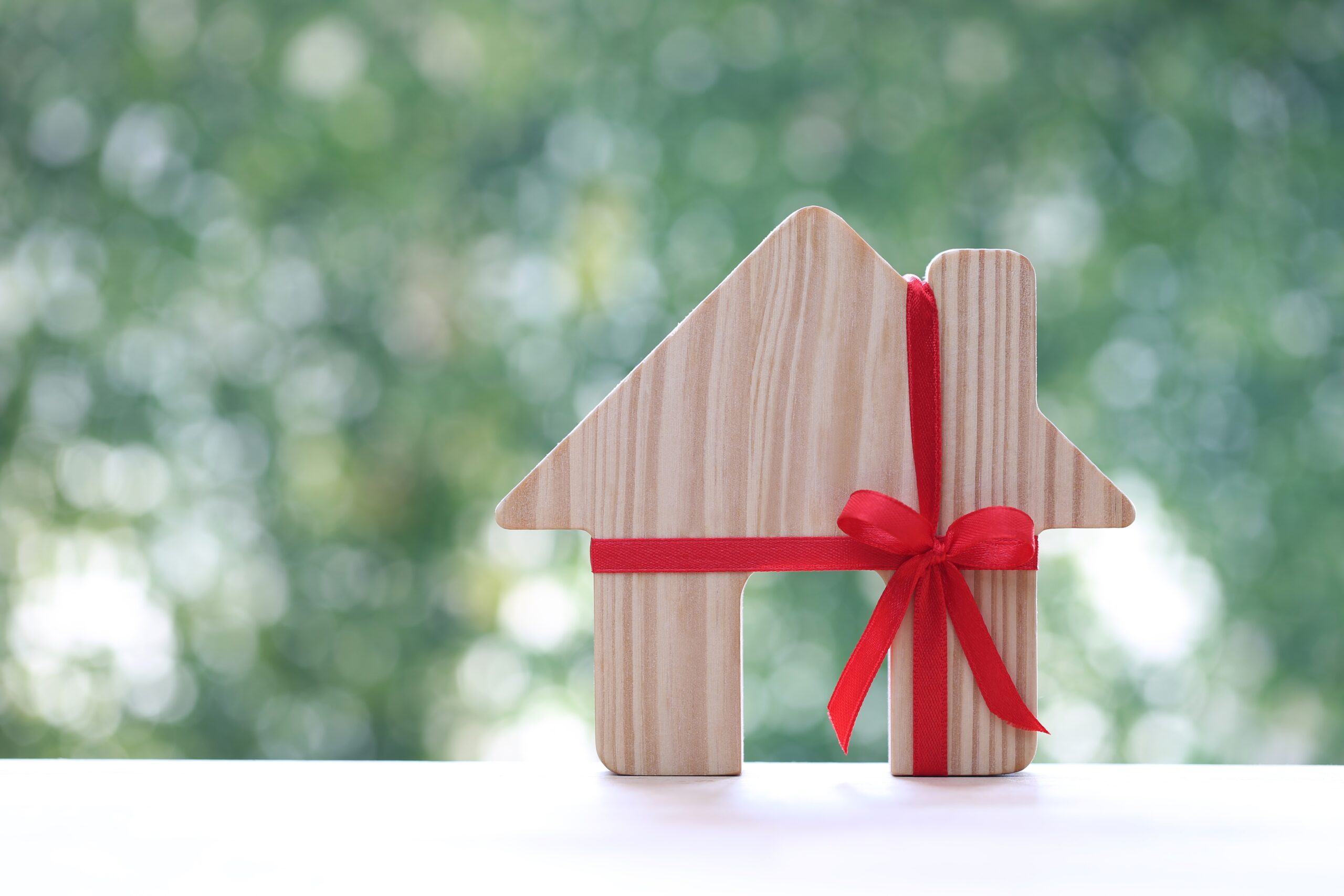 wooden cut out house with a red ribbon tied in a bow around it