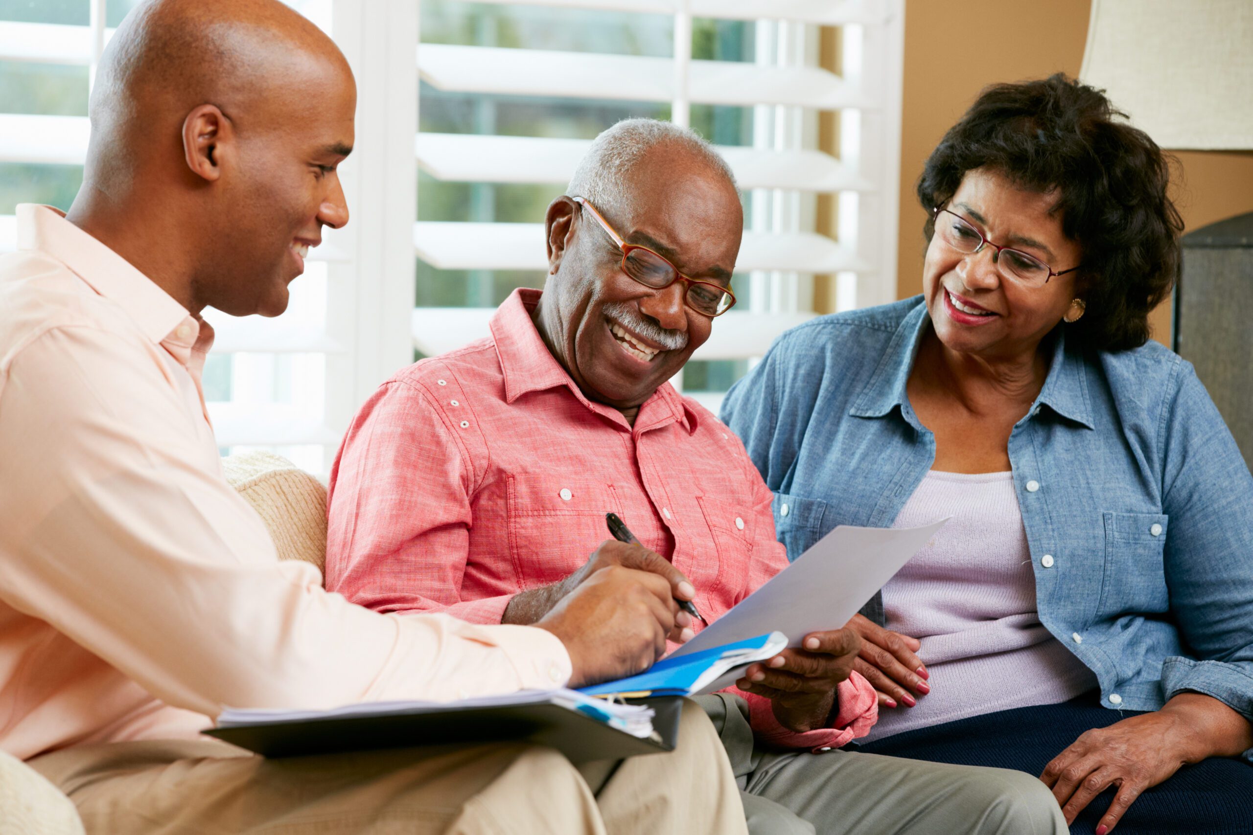 Mature African American Couple signs documents in hands of a younger man 