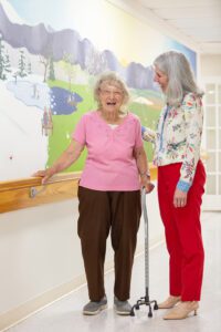 Older woman laughs while speaking with program manager in a hallway
