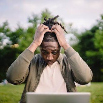 Man holding his head in frustration staring at a laptop computer