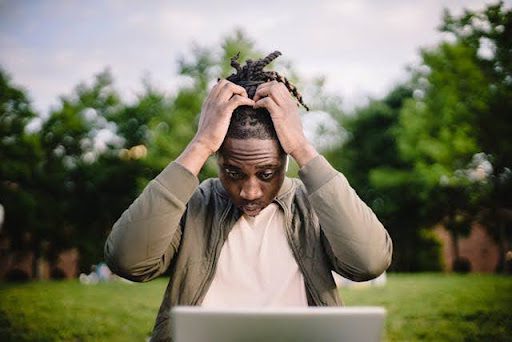 Man holding his head in frustration staring at a laptop computer