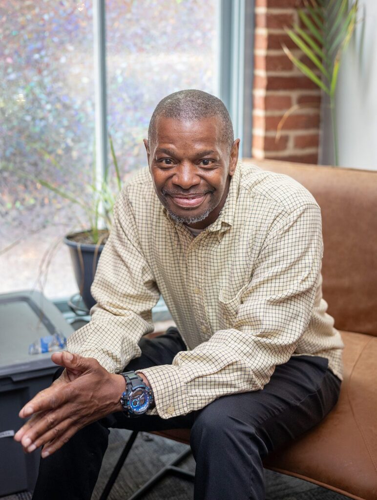 Man sits smiling on a couch