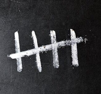 five white chalk tally marks on a black board