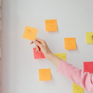 multi-colored sticky notes on a wall with various financial terms on them. A woman's hand is picking one up to read