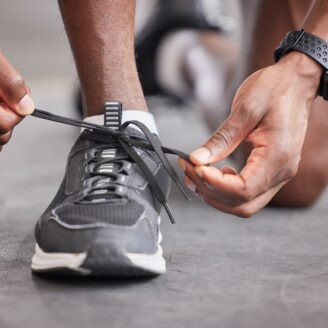 man laces up his running shoes