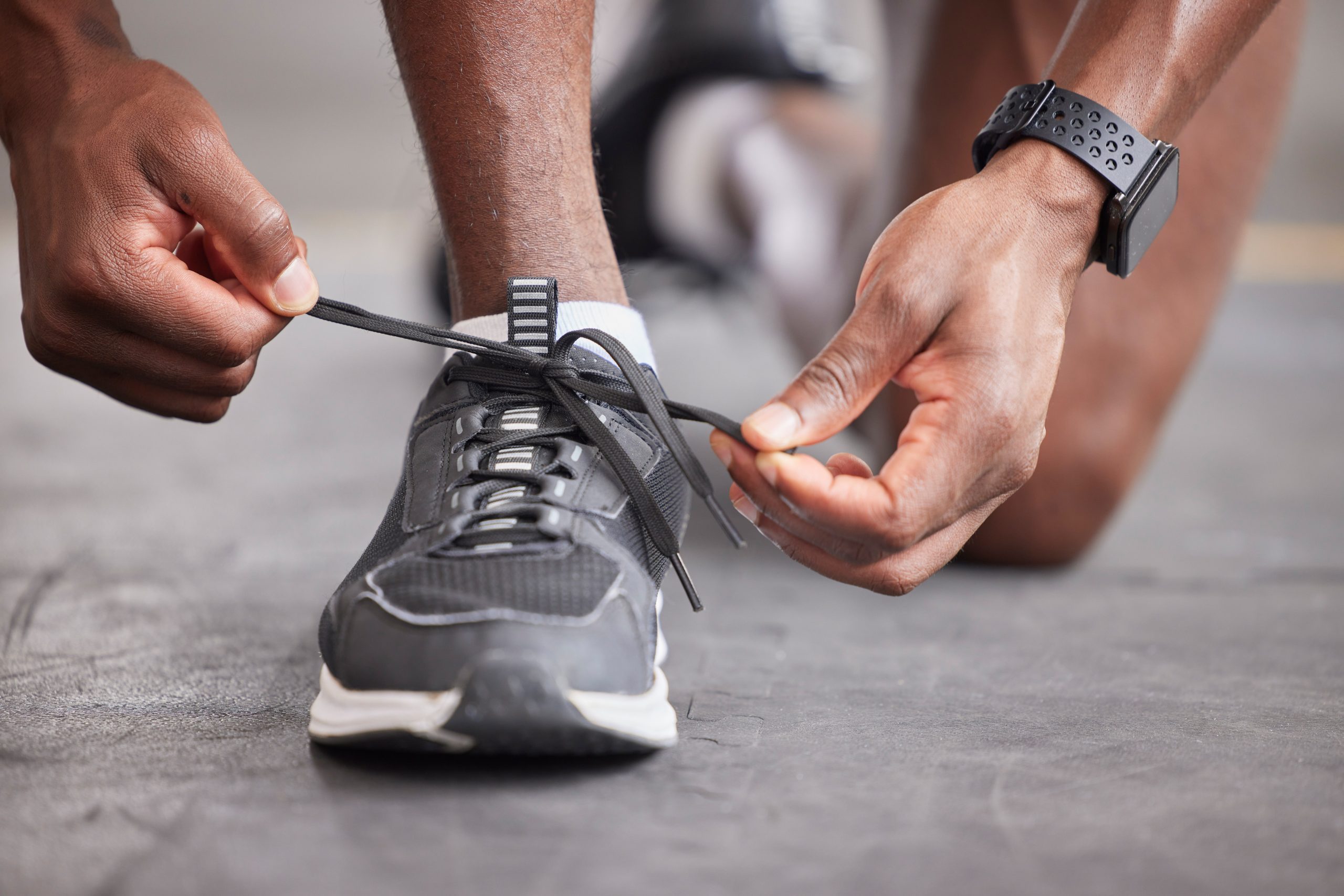 man laces up his running shoes