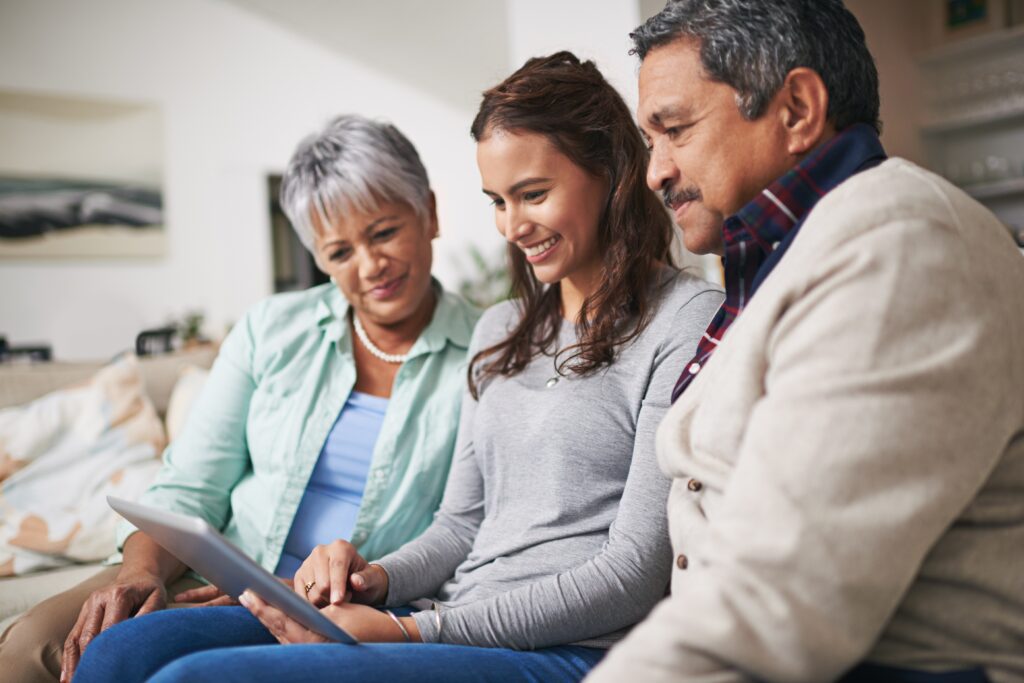 two older adults look at a tablet held by a younger adult