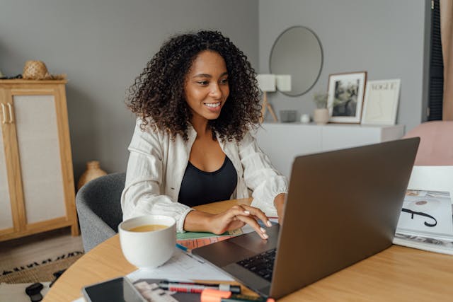black woman sitting at a laptop typing and smiling