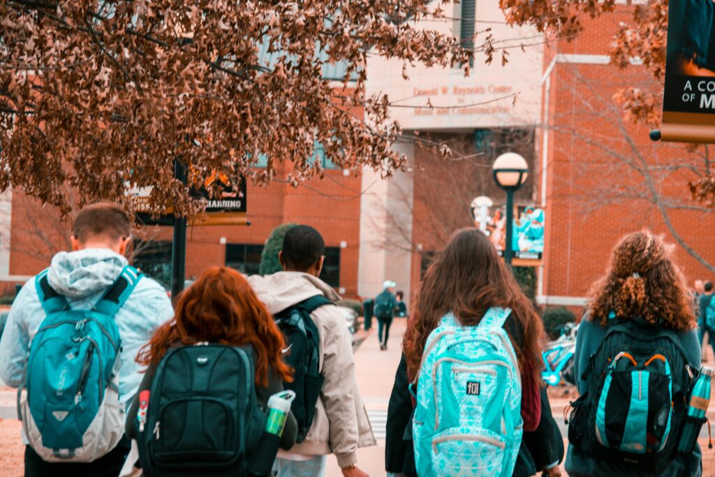students wearing backpacks walking towards a brick school building